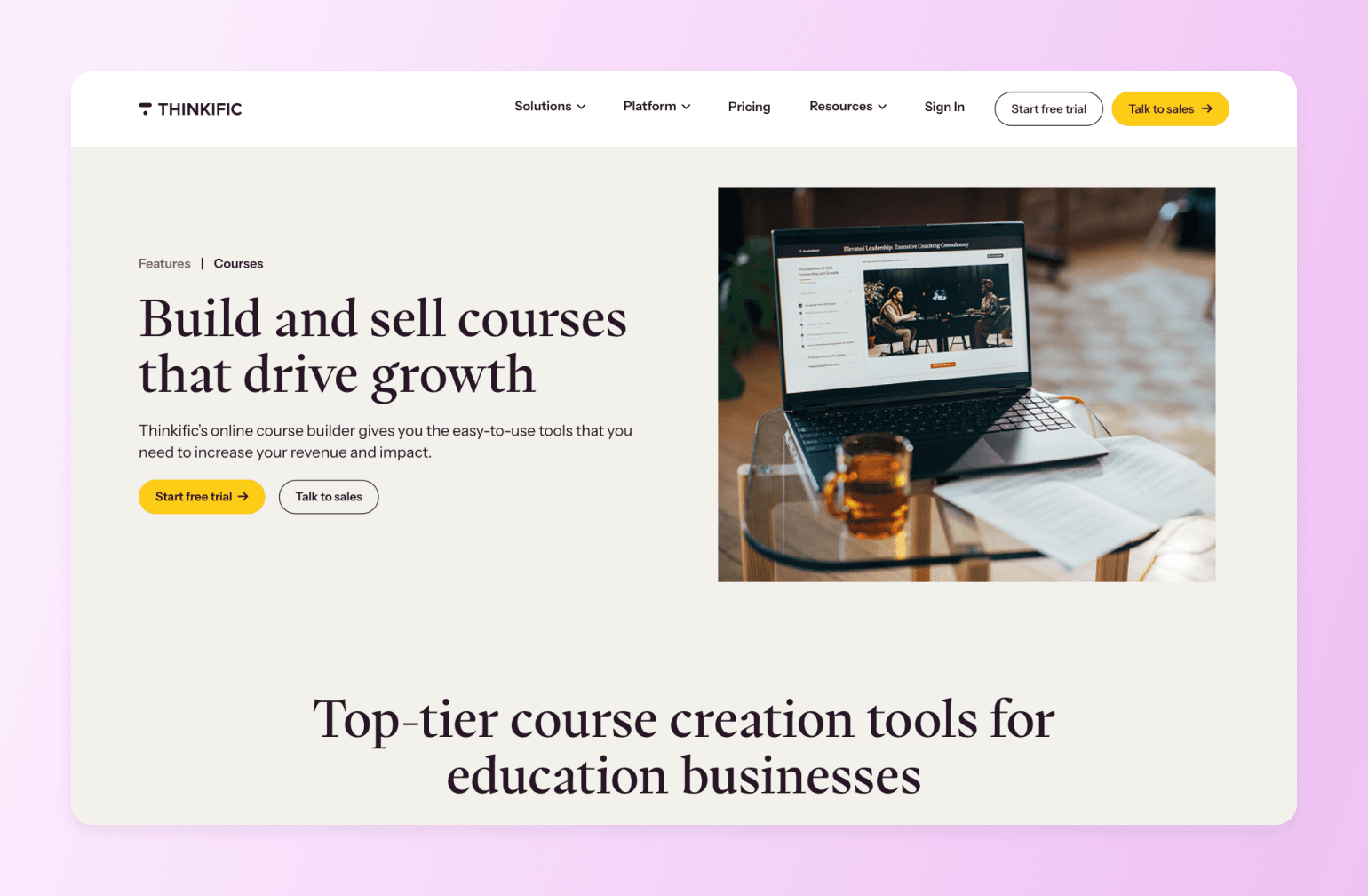 Laptop displaying Thinkific course builder platform with glass of whiskey and notebook on wooden desk